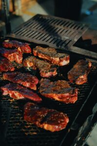 Image of steaks cooking on top of a grill