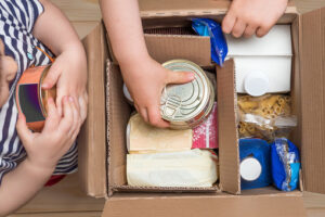 Hands adding food to donation box.