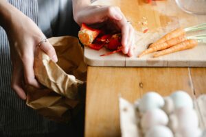 person scraping food scraps into trash can