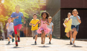 Team of positive kids running in race and laughing outdoors