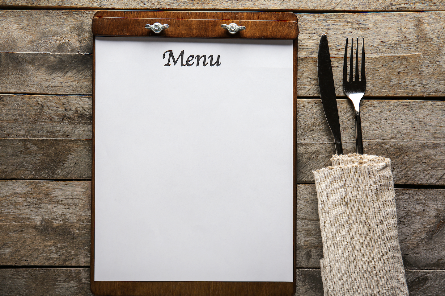 Blank menu board beside fork and knife wrapped in cloth napkin